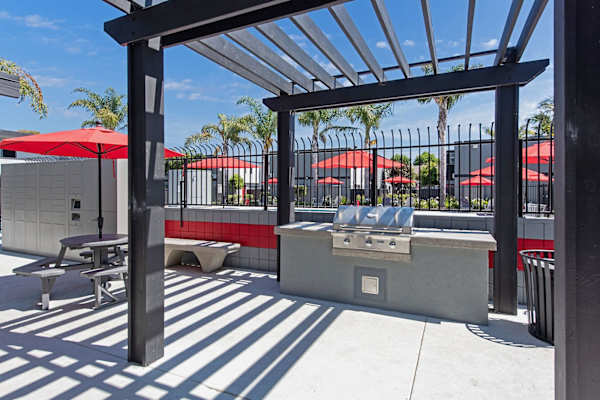 a patio with a grill and tables with umbrellas